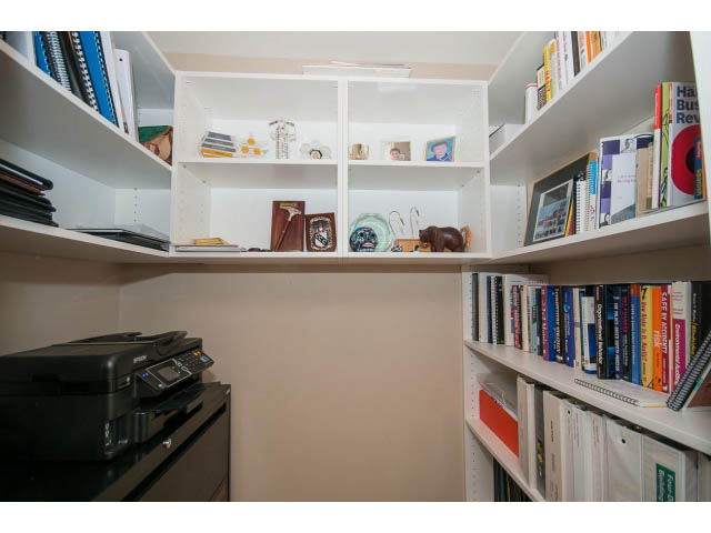 Bright and organized living room with bookshelves and a desk. - 201 - 150 West 22nd Street, North Vancouver