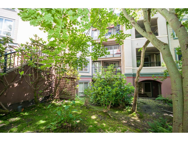 Furnished living room with lush greenery and balcony access. - 201 - 150 West 22nd Street, North Vancouver