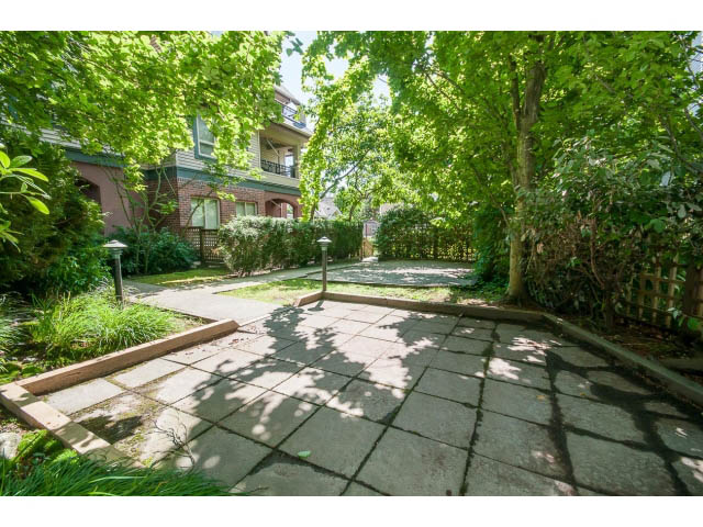 Furnished patio with stone paving and lush greenery. - 201 - 150 West 22nd Street, North Vancouver