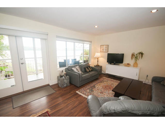 Furnished living room with hardwood floors, large windows, and a view of the water. - Suite - 2985 Dollarton Hwy, North Vancouver