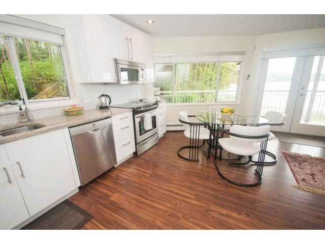 Bright kitchen with white cabinets, stainless steel appliances, and hardwood floors. - Suite - 2985 Dollarton Hwy, North Vancouver