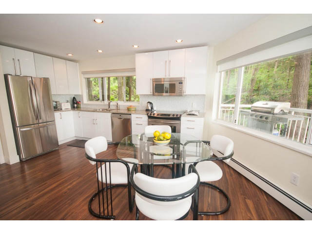 Bright kitchen with stainless steel appliances, hardwood floors, and a view of the outdoors. - Suite - 2985 Dollarton Hwy, North Vancouver