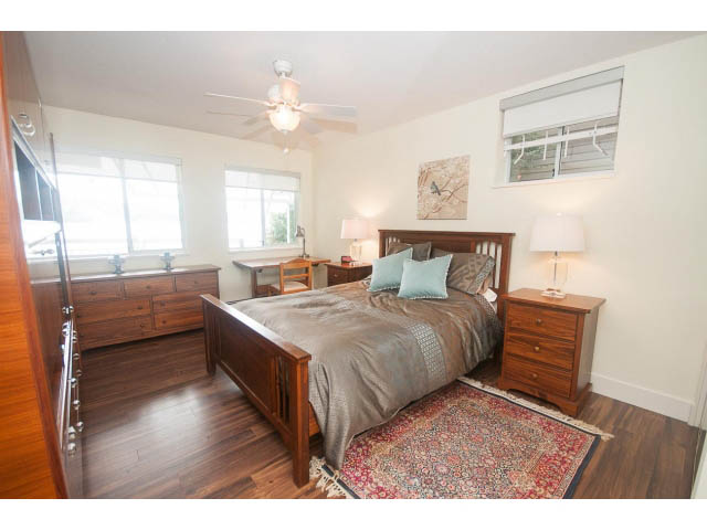 Bright bedroom with hardwood floors, wooden furniture, and a cozy rug. - Suite - 2985 Dollarton Hwy, North Vancouver