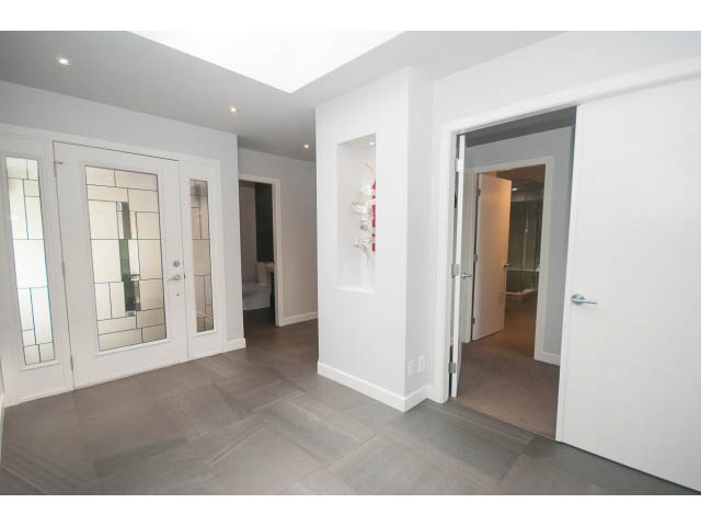 Bright entryway with white walls, glass-paneled doors, and hardwood floors. - 2948 Marykirk Place, North Vancouver