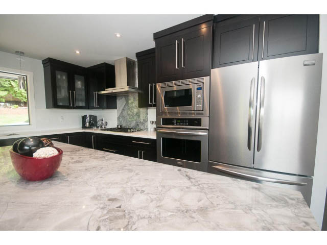 Bright kitchen with dark cabinets, stainless steel appliances, and marble countertops. - 2948 Marykirk Place, North Vancouver