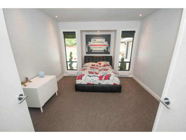 Bright bedroom with twin beds, white walls, and a framed car artwork. - 2948 Marykirk Place, North Vancouver