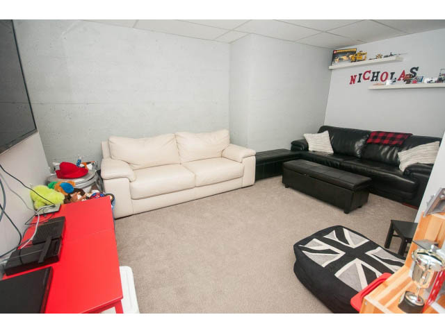 Furnished living room with white couch, black ottoman, and Union Jack throw pillow. - 2948 Marykirk Place, North Vancouver