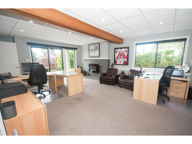 Spacious office with wooden desks, large windows, and a cozy seating area. - 2948 Marykirk Place, North Vancouver