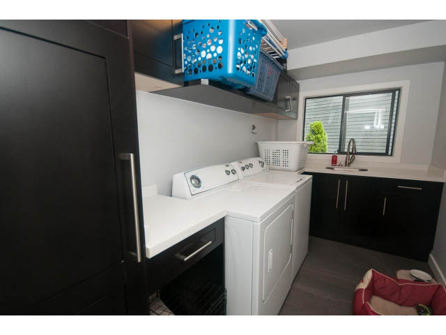 Bright laundry room with white countertops, black cabinets, and a window view. - 2948 Marykirk Place, North Vancouver