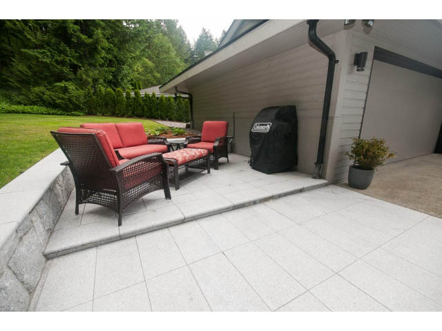 Furnished patio with outdoor seating and grill, surrounded by greenery. - 2948 Marykirk Place, North Vancouver