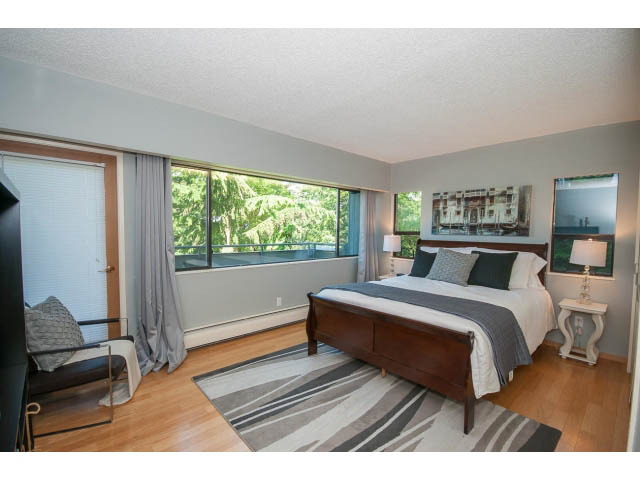 Spacious bedroom with hardwood floors, large windows, and a cozy bed setup. - 5338 Montiverdi Pl, West Vancouver