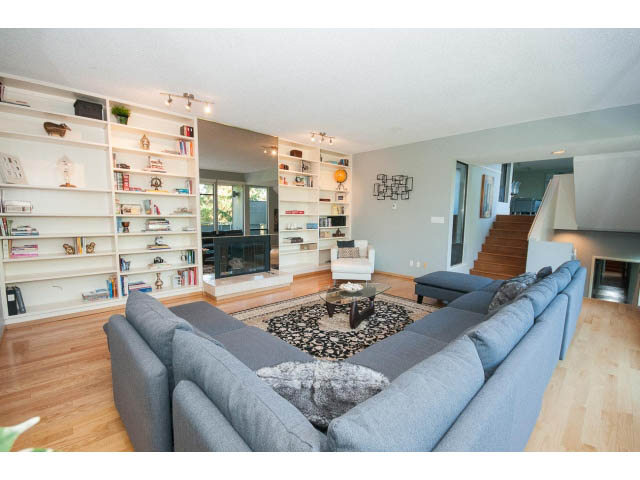 Spacious living room with hardwood floors, large bookshelves, and a cozy sectional sofa. - 5338 Montiverdi Pl, West Vancouver