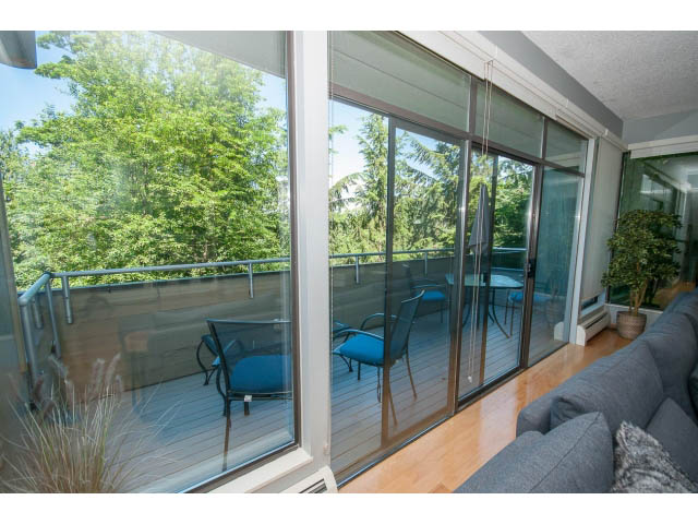Bright living room with large sliding glass doors, hardwood floors, and a view of greenery. - 5338 Montiverdi Pl, West Vancouver