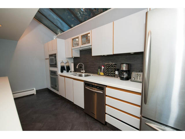 Bright kitchen with white cabinets, stainless steel appliances, and dark countertops. - 5338 Montiverdi Pl, West Vancouver