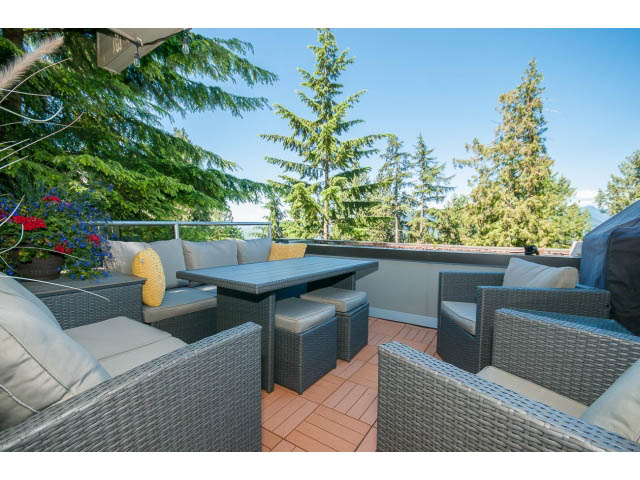 Furnished patio with wicker furniture and a view of evergreen trees. - 5338 Montiverdi Pl, West Vancouver
