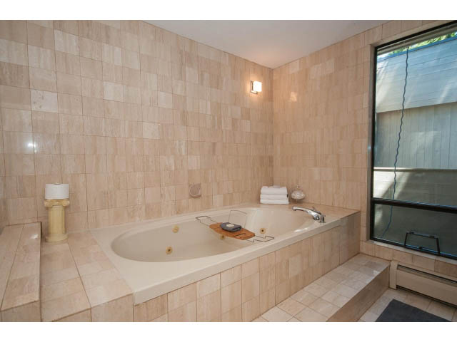 Spacious bathroom with beige tile walls and a corner tub. - 5338 Montiverdi Pl, West Vancouver