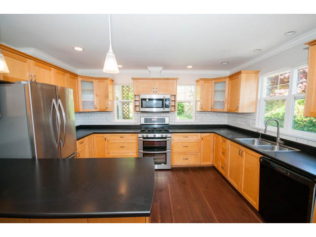 Bright kitchen with dark countertops, hardwood floors, and a city view. - 3626 Loraine Ave, North Vancouver