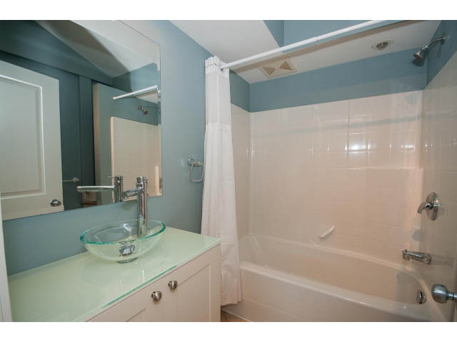 Bright bathroom with white countertop and bathtub, featuring a shower curtain and modern fixtures. - 3626 Loraine Ave, North Vancouver