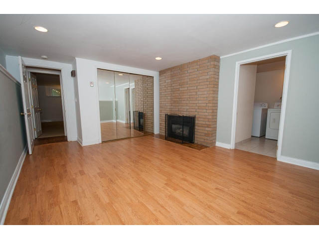 Open living space with hardwood floors and a brick accent wall. - 3626 Loraine Ave, North Vancouver