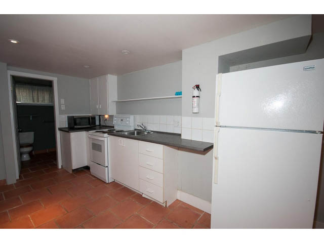 Bright kitchen with white cabinets, terracotta tile floor, and stainless steel sink. - 3626 Loraine Ave, North Vancouver