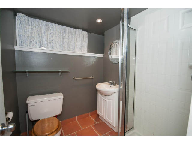 Small bathroom with white fixtures and tiled walls, featuring a toilet and a shower. - 3626 Loraine Ave, North Vancouver