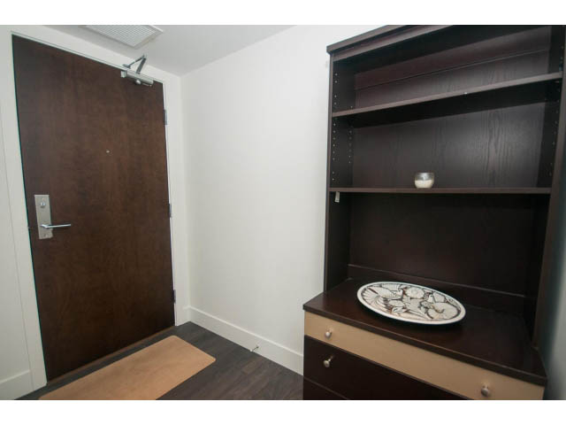 Den with dark wood shelving and a small table, hardwood floors, and a door leading outside. - 1504-1550 Fern Street, North Vancouver