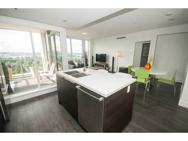 Furnished living room with hardwood floors, city view, and modern kitchen counter. - 1504-1550 Fern Street, North Vancouver