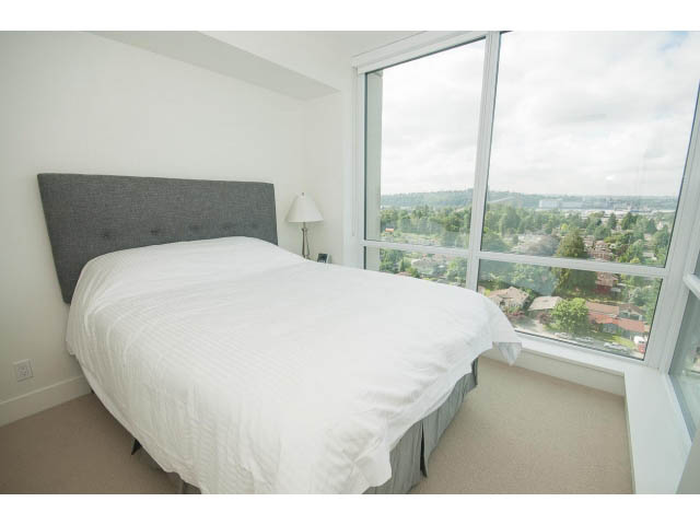 Bright bedroom with large windows offering a scenic city view, featuring a comfortable bed and modern decor. - 1504-1550 Fern Street, North Vancouver