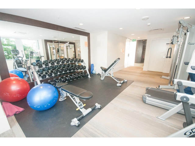 Furnished fitness room with exercise equipment, hardwood floors, and large windows. - 1504-1550 Fern Street, North Vancouver