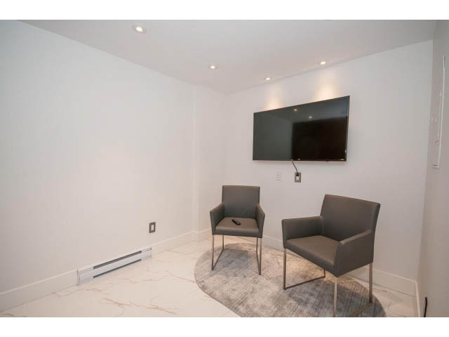 Bright living room with modern furniture and a large TV mounted on the wall. - 307 - 1490 Pennyfarthing Drive, Vancouver West Side