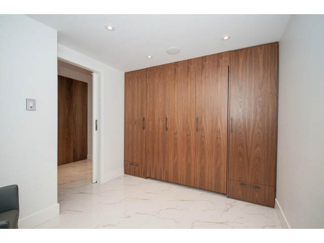 Spacious living room with marble floors and wooden wall paneling. - 307 - 1490 Pennyfarthing Drive, Vancouver West Side