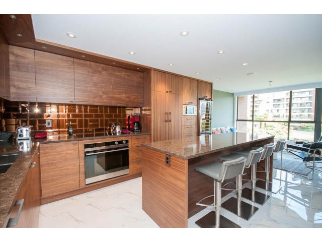 Bright kitchen with wooden cabinets, granite countertops, and a city view. - 307 - 1490 Pennyfarthing Drive, Vancouver West Side
