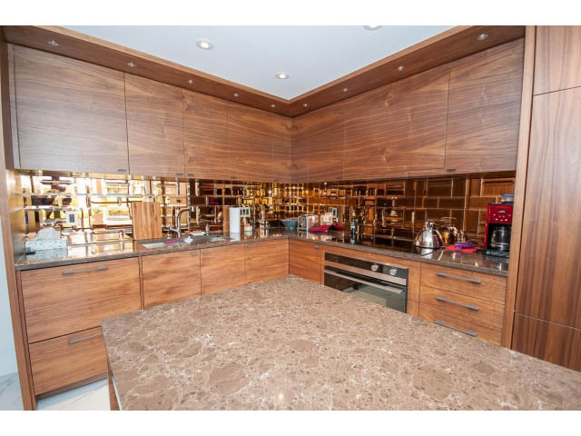 Bright kitchen with marble countertops and wooden cabinets, featuring a modern design. - 307 - 1490 Pennyfarthing Drive, Vancouver West Side