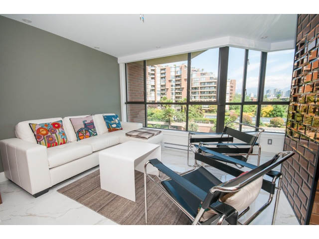 Bright living room with white furniture, city view, and large windows. - 307 - 1490 Pennyfarthing Drive, Vancouver West Side