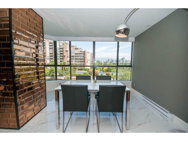 Modern dining area with sleek table, black chairs, and city view through large windows. - 307 - 1490 Pennyfarthing Drive, Vancouver West Side