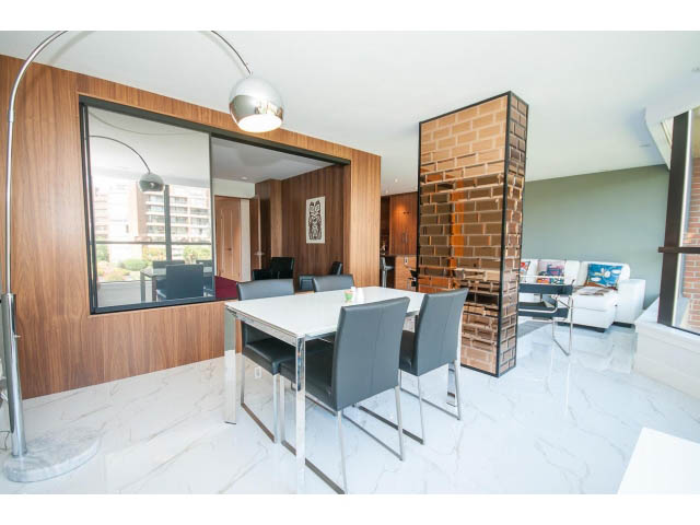 Furnished living room with marble countertops and brick accent wall, city view. - 307 - 1490 Pennyfarthing Drive, Vancouver West Side