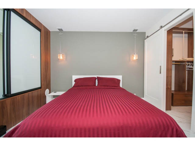 Spacious 2-bedroom condo with red striped bedding and modern lighting. - 307 - 1490 Pennyfarthing Drive, Vancouver West Side
