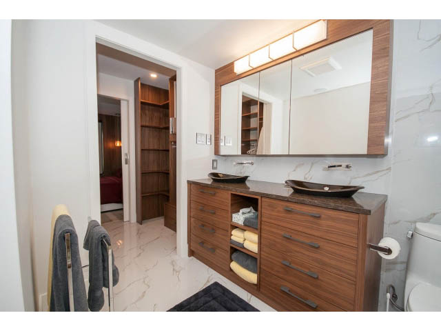 Furnished bathroom with marble countertops and wooden cabinets. - 307 - 1490 Pennyfarthing Drive, Vancouver West Side