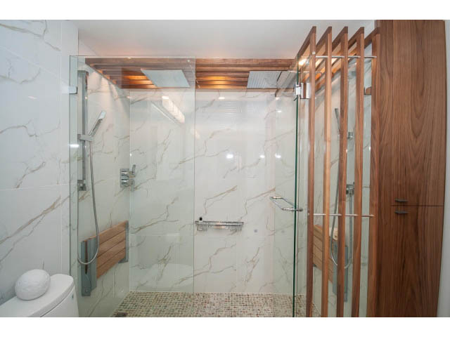 Spacious bathroom with marble tiles, glass shower, and wooden accents. - 307 - 1490 Pennyfarthing Drive, Vancouver West Side