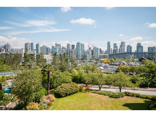 Bright living room with city view and lush greenery. - 307 - 1490 Pennyfarthing Drive, Vancouver West Side