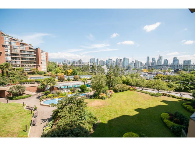 Bright living room with city view and lush greenery. - 307 - 1490 Pennyfarthing Drive, Vancouver West Side