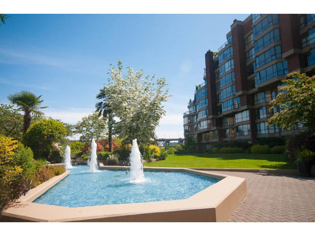 Furnished living room with a large fountain and lush greenery. - 307 - 1490 Pennyfarthing Drive, Vancouver West Side