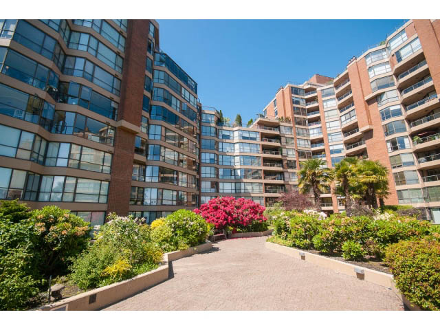 Spacious 2-bedroom condo with modern furnishings and lush greenery surrounding the entrance. - 307 - 1490 Pennyfarthing Drive, Vancouver West Side