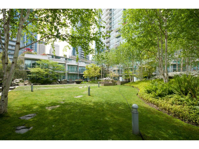 Bright and serene courtyard with lush greenery and modern city skyline in the background. - 803 - 590 Nicola Street, Vancouver Downtown