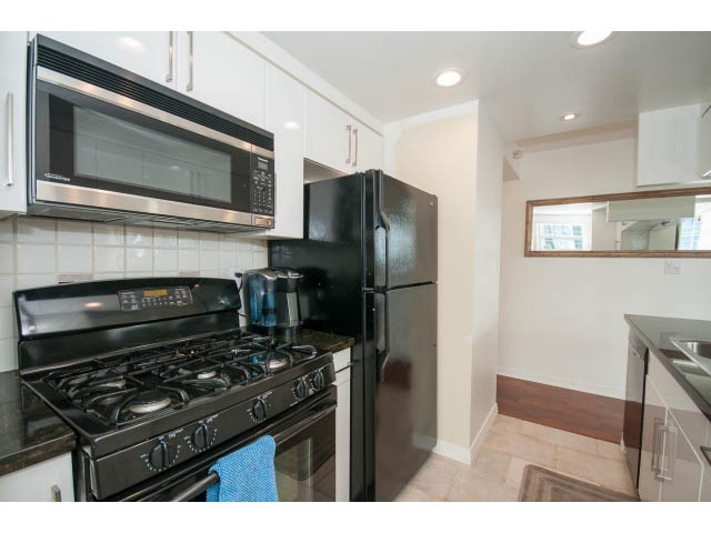 Bright kitchen with black appliances, granite countertops, and hardwood floors. - 1506 - 1199 Marinaside Cres, Vancouver Downtown