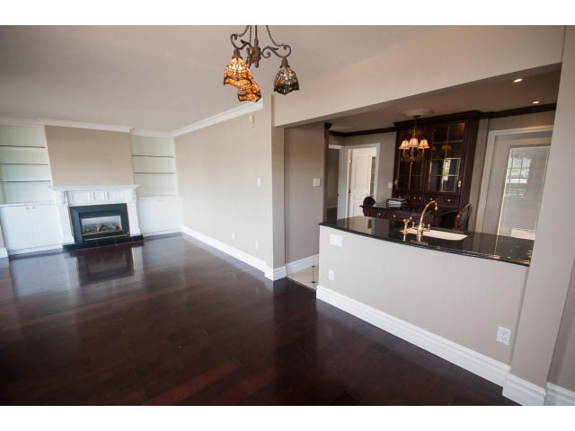 Spacious living room with hardwood floors and a fireplace, featuring a modern chandelier. - 1122 Ironwork Passage, Vancouver West Side