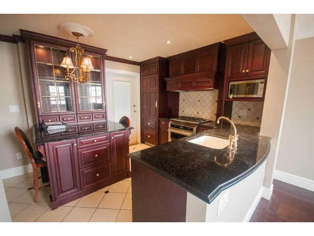 Bright kitchen with dark wood cabinets, granite countertops, and hardwood floors. - 1122 Ironwork Passage, Vancouver West Side