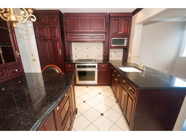Bright kitchen with dark granite countertops and rich wood cabinets. - 1122 Ironwork Passage, Vancouver West Side