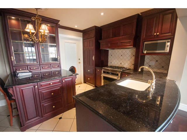Bright kitchen with dark wood cabinets, black granite countertops, and a chandelier. - 1122 Ironwork Passage, Vancouver West Side