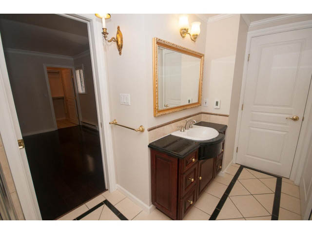 Bathroom with dark wood vanity, white walls, and gold accents. - 1122 Ironwork Passage, Vancouver West Side